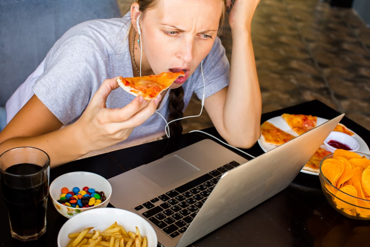 jeune femme qui mange de la pizza devant son ordinateur